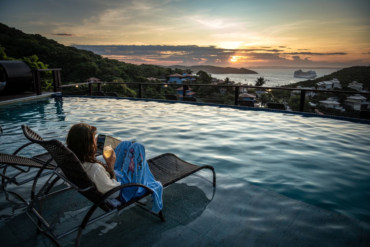 A glass of wine at an infinity pool over the bay at sunset